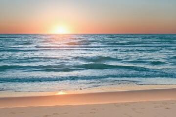 Colorful sunset viewed from the pink sea beach with soft waves