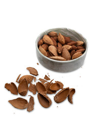 Raw almonds in shells inside a marble bowl with broken nutshells scattered on transparent background. Natural healthy food concept, organic snack composition.
