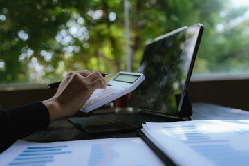 Business person analyzing financial charts and graphs on paper with a pen, working on data and strategy planning at the office.