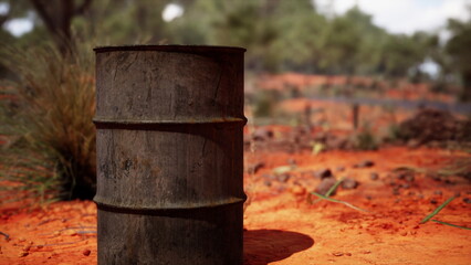 Naklejka premium In a dry, arid terrain, a solitary battered barrel stands amidst the striking red earth, surrounded by sparse vegetation. The sun casts harsh shadows, emphasizing its worn texture.