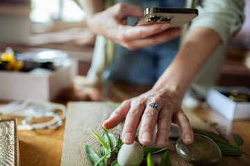 Young woman photographing handmade jewelry