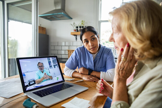 Senior woman and her caregiver talking to a doctor over a video call on their laptop