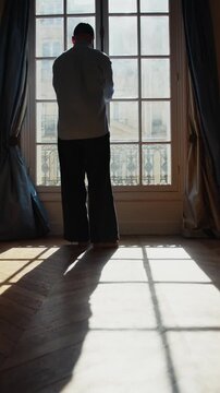 Man opening a window and looking at the city