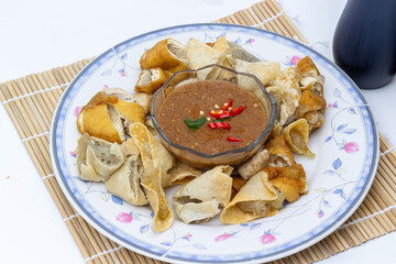 A savory platter of Indonesian Batagor, featuring crispy fried tofu and dumplings with a rich and spicy peanut sauce for dipping