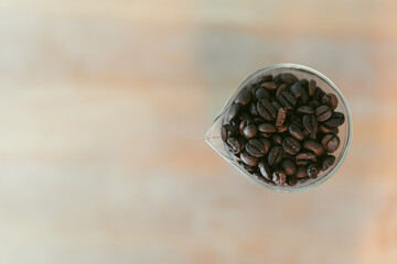 Glass jar filled with coffee beans on a wooden table, warm lighting enhances the cozy atmosphere