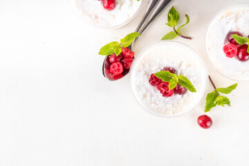 Christmas portioned cheesecakes in glass, made from golden sugar cookie crumble, layered with white mascarpone cream cheese, sugar powder and cranberry decor, copy space