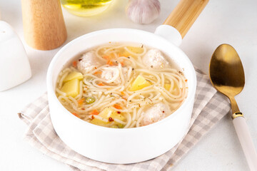 Homemade soup with chicken or turkey meatballs, pasta, vegetables and greens. White meat broth with vegetables and macaroni, healthy diet food, children's lunch