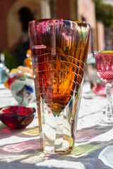 Colorful glass vase displayed on flea market stall, gently lit by the morning sun, revealing its...