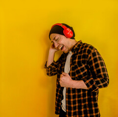 Fototapeta premium Side View Of Happy Asian Man Enjoying Listen Music From Headphones And Singing Isolated On Yellow Background