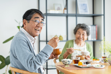 家で朝食を食べるシニアの夫婦