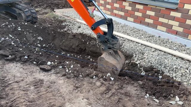 Mini tractor digs a trench to build track. Excavation of the trench