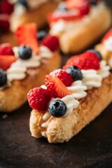 Tiramisu-style dessert with savoiardi, cream cheese and berries on dark background. Sweets and desserts.