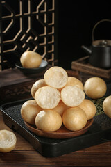 Hot fresh bread puffs with torn texture on wooden plate in rustic kitchen with cooking pot and baking essentials