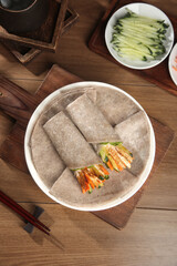 Whole wheat vegetable pancake wraps with chopsticks on rustic wooden table - healthy Asian breakfast preparation