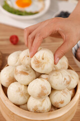 Traditional Chinese Steamed Buns Xiao Long Bao in Bamboo Steamer with Hand Selecting Dumpling for Breakfast Cuisine