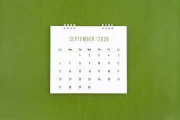 September 2026 Monthly desk calendar on green leather background. Flat lay.