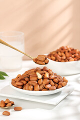 Large Pine Nuts in White Bowls with Golden Spoon on Marble Background - Handpeeled Red Natural Food Ingredients