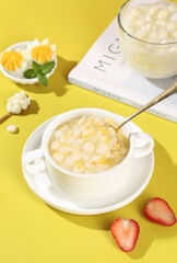 Fresh Corn Kernel Soup with Milk and Strawberries on Yellow Background