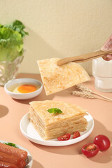 Hand with Tongs Lifting Flaky Layered Pastry Pie for Breakfast Meal