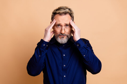Confident businessman in stylish formal attire expressing concentration and professionalism on a beige backdrop - Powered by Adobe