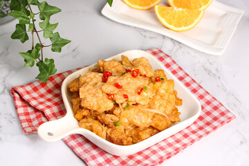 Golden Crispy Fried Pork Buns in White Pot with Chili Peppers and Orange Garnish