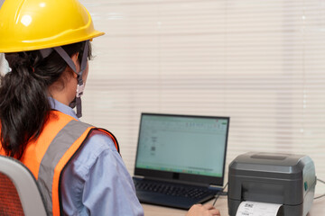 Beautiful Asian woman uses a laptop or notebook to print bar code stickers on a bar code printer.