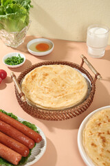 Handmade Golden Pancakes in Wicker Basket with Sausages and Fresh Herbs for Breakfast Brunch Meal