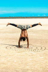 A man doing a yoga pose next to seashells on the beach at Watamu Beach in Kenya