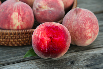 Fresh Chinese Blood Peaches with Red Carmine Flesh in Wicker Basket Display on Wooden Background
