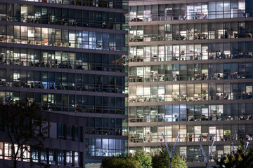 Obraz premium Nighttime view of illuminated office building with workers visible through glass windows during evening hours