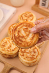 Hand Holding Golden Puff Pastry with Swirl Pattern on Wooden Board