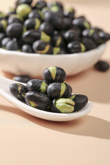 Black beans with green sprouts in white ceramic spoon on wooden table, healthy legume food ingredient