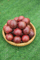 Fresh Red Plums from Chile in Woven Basket on Grass - Imported Stone Fruit