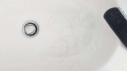 Loose strands by drain and comb in bathroom sink suggest male pattern thinning and daily shedding, clinical neutral mood