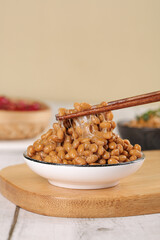 Japanese natto fermented soybeans with chopsticks showing sticky texture in traditional serving bowl