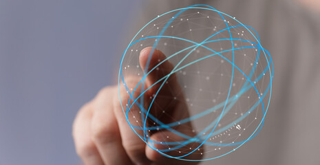 A person's hand interacts with a digital network sphere, symbolizing connectivity, global communication, and technology. Suitable for technology
