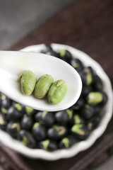 Five Crispy Green Beans with Heart-Shaped Black Bean Stir-Fry and Salt Spices on White Ceramic Spoon