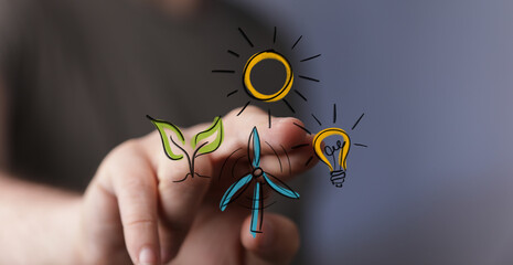 Finger touches a virtual screen displaying hand-drawn renewable energy icons: sun, wind turbine,...