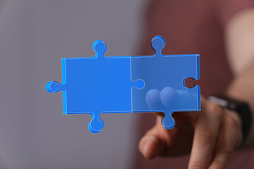 Conceptual image of a hand fitting two puzzle pieces together, representing connection,...