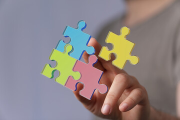 Hand holding colorful puzzle pieces. Teamwork, solution, connection, strategy, success concept.