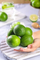 Fresh Green Limes in Hands on Wooden Board - Healthy Citrus Fruit Kitchen Concept