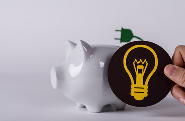 Conceptual image showing energy conservation with a piggy bank, a lightbulb idea and a green plug. It represents smart savings and innovation in
