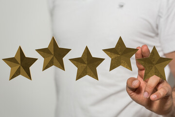 A hand reaching out to golden stars, representing a rating or review, conveying concept of quality,...