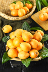 Fresh Organic Loquat Fruits in Wicker Baskets with Green Leaves on Rustic Wood Background