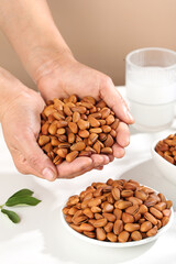 Fresh Pine Nuts in Cupped Hands with Bowl and Milk Glass - Healthy Natural Food Ingredients