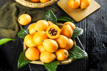 Fresh Organic Loquat Fruits in Wicker Basket with Leaves on Rustic Wood Table
