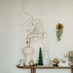 Elegant holiday decor with ceramic trees, candles and golden ornaments. Calm neutral palette and natural, modern style.