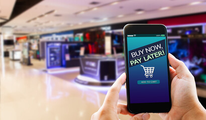 BNPL Buy now pay later online shopping concept.Hands holding mobile phone on blurred store as background