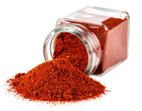 Red spice powder spilling from a clear glass jar