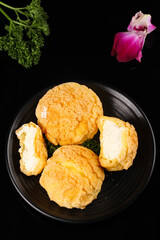 Fresh Cream Puff Pastries with Custard Filling on Elegant Black Plate Food Photography